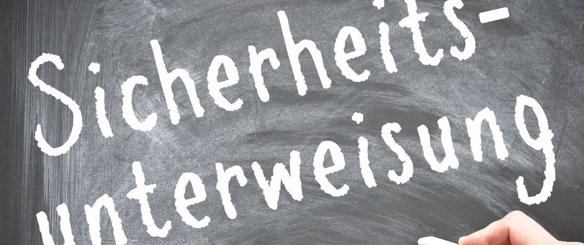 Mit Kreide wurde auf deine schwarze Tafel das Wort Sicherheitsunterweisung geschrieben