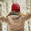 Freu im verschneiten Winterwald, die freudig die Arme ausbreitet
