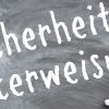 Mit Kreide wurde auf deine schwarze Tafel das Wort Sicherheitsunterweisung geschrieben