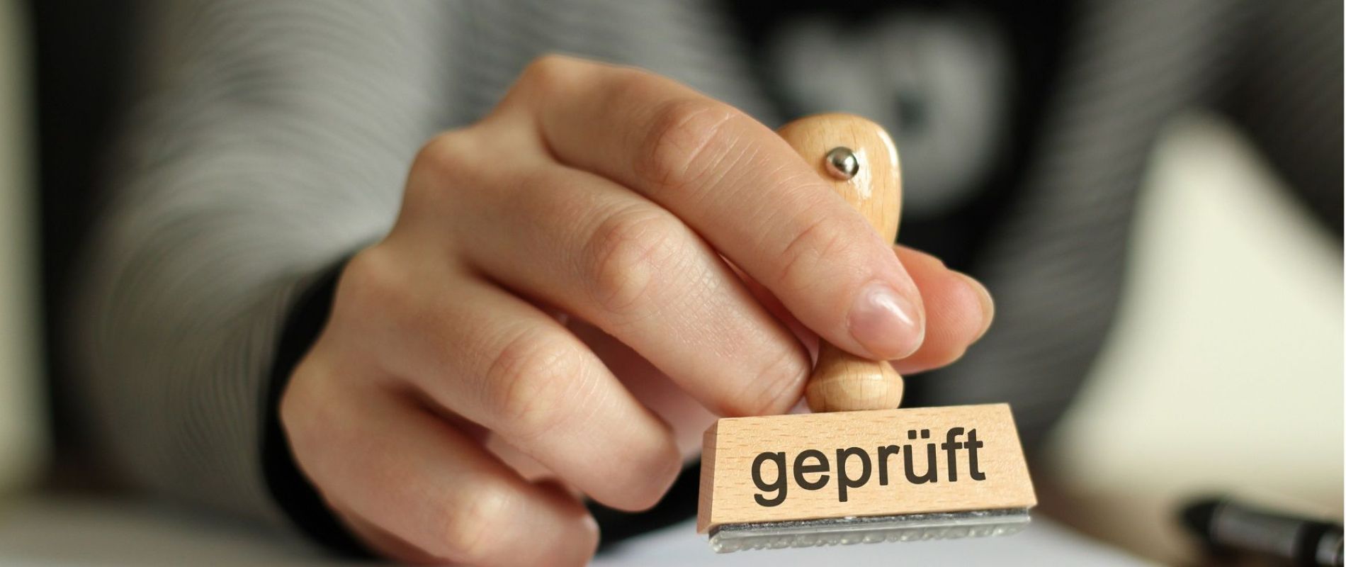 Hand die einen Stempel hält, auf dem geprüft steht