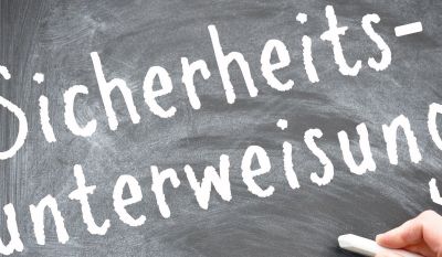 Mit Kreide wurde auf deine schwarze Tafel das Wort Sicherheitsunterweisung geschrieben