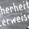 Mit Kreide wurde auf deine schwarze Tafel das Wort Sicherheitsunterweisung geschrieben